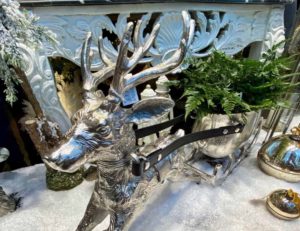 A silver deer pulling a sled of plants