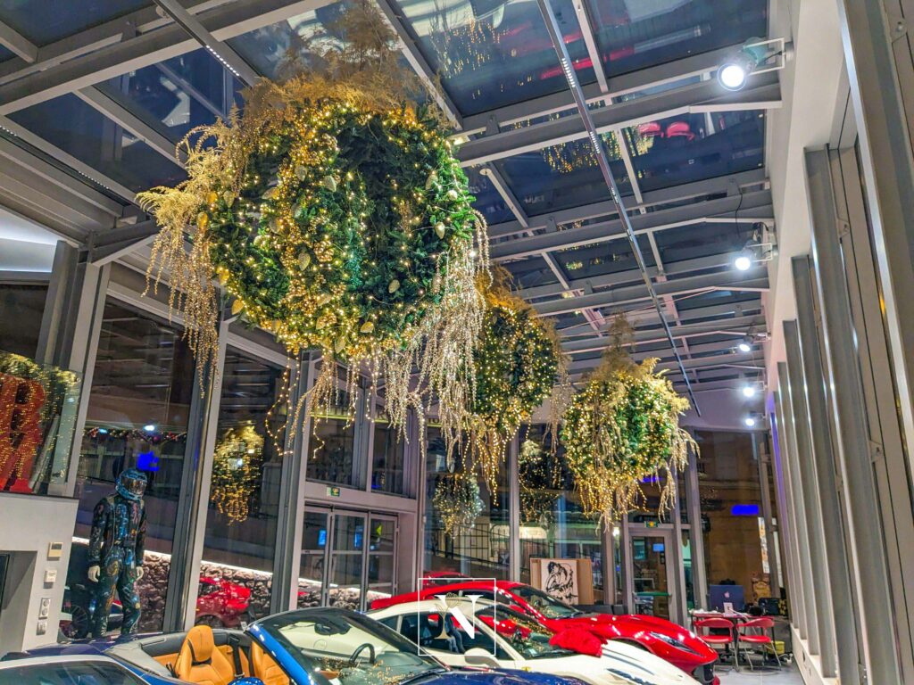 Décorations de Noël Narmino sous forme de luminaires scintillants, parmi de magnifiques véhicules haut de gamme, installés chez DPM Motors à Monaco.